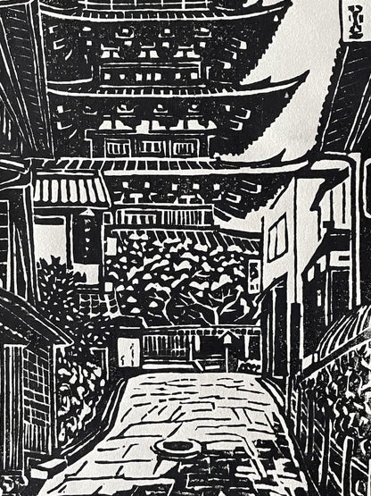 Estampe japonaise en noir et blanc de Hiroshi Yuasa, célébrant la pagode Yasaka de Kyoto, symbole de spiritualité et d’élégance architecturale. Avec ses cinq étages gracieux et ses détails minutieux, cette œuvre en édition limitée (30 exemplaires) incarne l’harmonie entre tradition et nature.