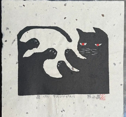 Estampe japonaise contemporaine de Iwao Akiyama représentant un chat noir stylisé faisant une galipette, avec des yeux rouges, sur papier washi artisanal.
